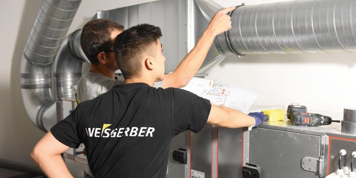 Ein Team von Technikern analysiert gemeinsam die Installation von Lüftungssystemen, um sicherzustellen, dass alles korrekt ausgeführt wird.