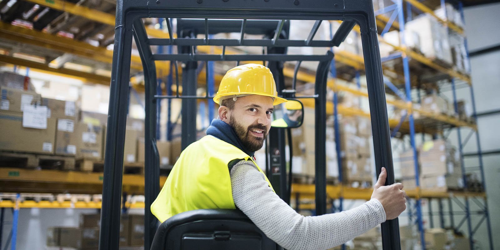 Ein Lagerist sitzt auf einem Stabler in einer Lagerhalle