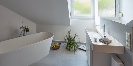 Ein modernes Badezimmer mit einer freistehenden Badewanne und einem eleganten Waschbecken, das viel Tageslicht erhält.