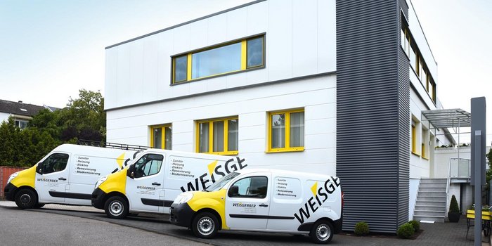 Drei Lieferwagen mit dem Logo 'WEISGERBER' stehen vor einem modernen, hellen Gebäude mit gelben Fenstern.
