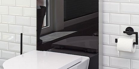 Ein schickes, wandmontiertes Toilettenmodell mit glatten Linien, reflektiert in einem schwarzen Spiegel und umgeben von hellen Fliesen.